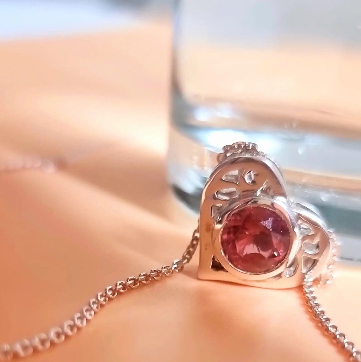 Close-up of 18K Gold Heart Pendant with 4ct natural pink tourmaline, highlighting intricate cutout design and fine chain for luxury jewelry.
