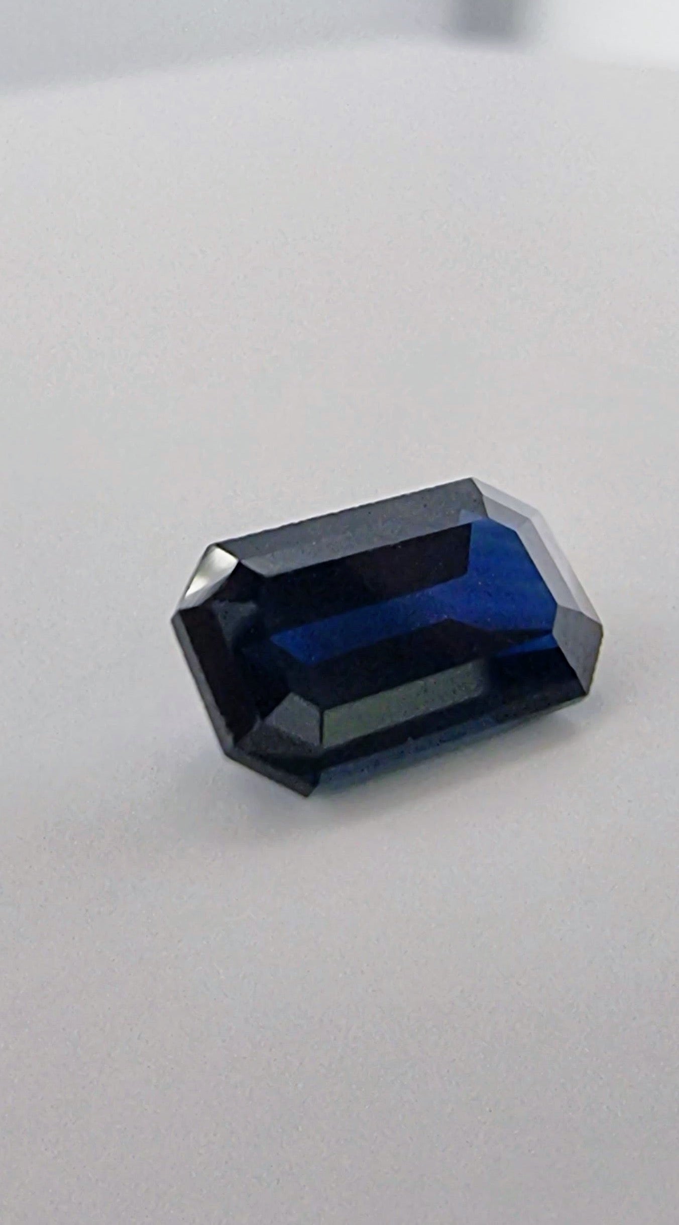 Close-up of 2.1ct rectangular cut dark blue natural sapphire gemstone showcasing its clarity and rich blue hue for gemstone collectors.