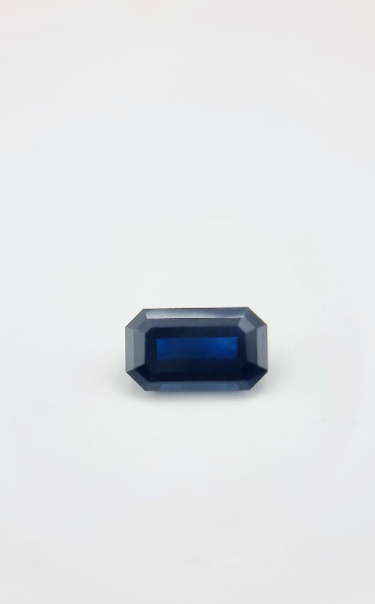 Top view of 2.1ct rectangular cut dark blue natural sapphire gemstone displaying its symmetrical cut and deep color saturation.