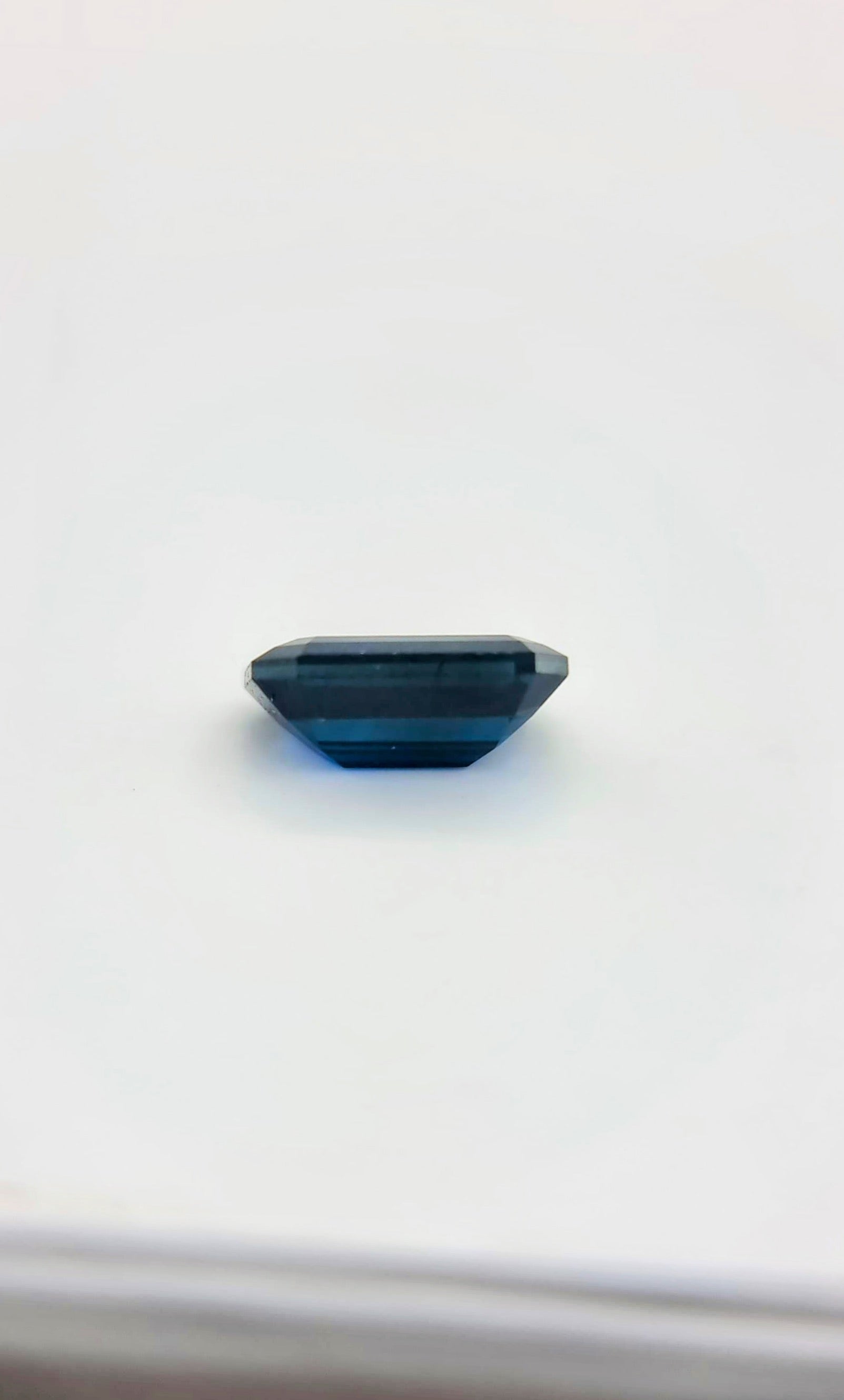 Profile view of 2.1ct rectangular cut dark blue natural sapphire gemstone showing its depth and precision cut for gemstone enthusiasts.
