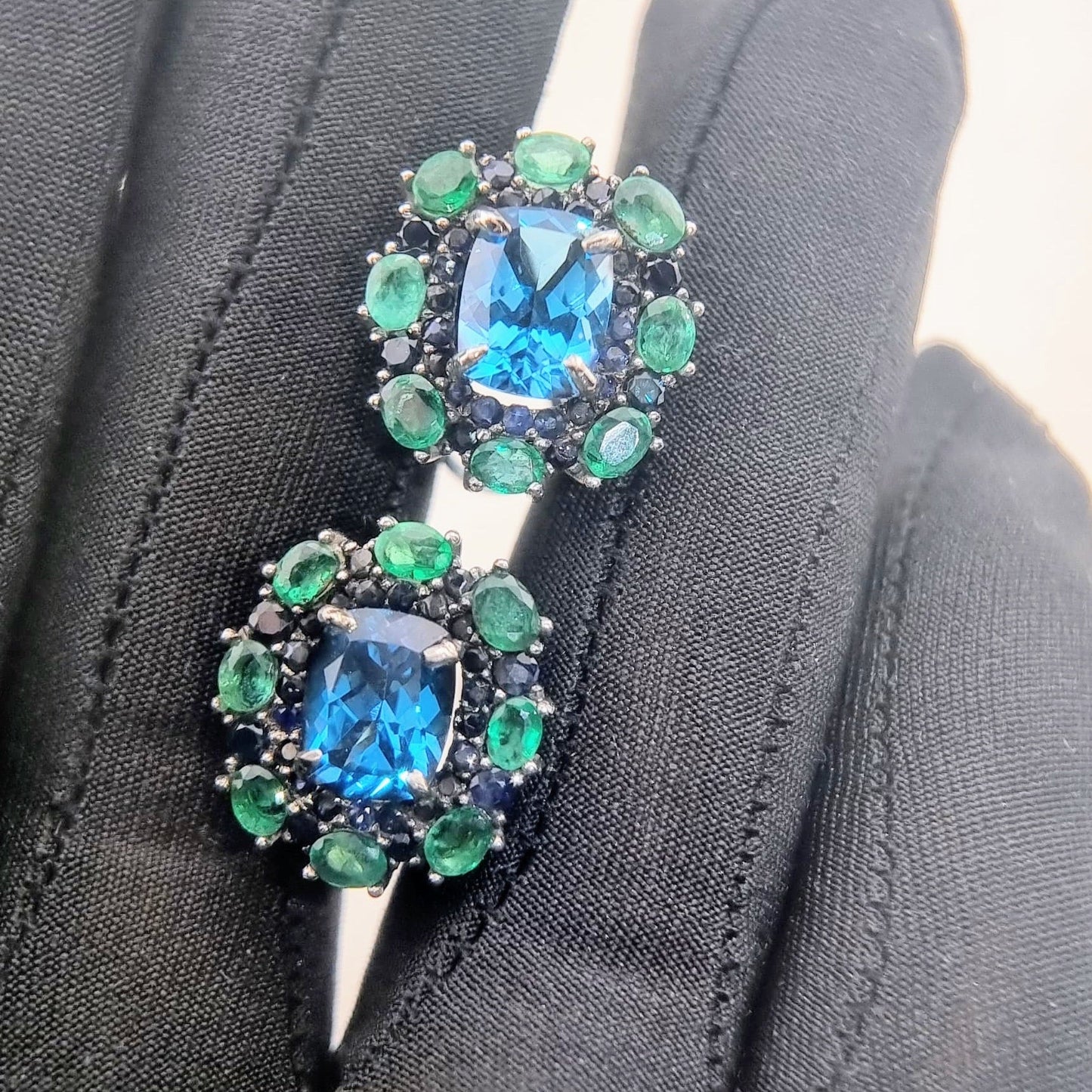 Natural Topaz Emerald & Sapphire Platinum Earrings held in gloved hand, emphasizing gemstone clarity and premium jewelry finish.