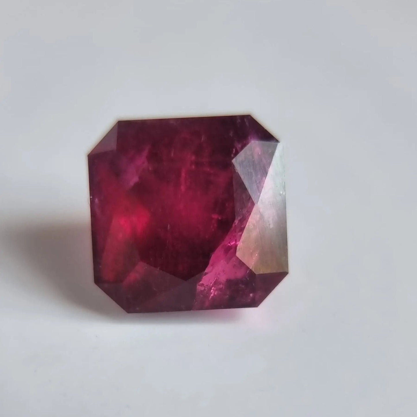 Close-up of 13.16ct Rubellite gemstone in square cut, showcasing its intense red color and polished finish for creative arts or jewelry.