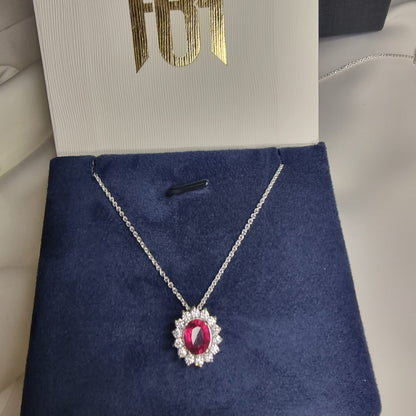 a necklace with a red stone in a box