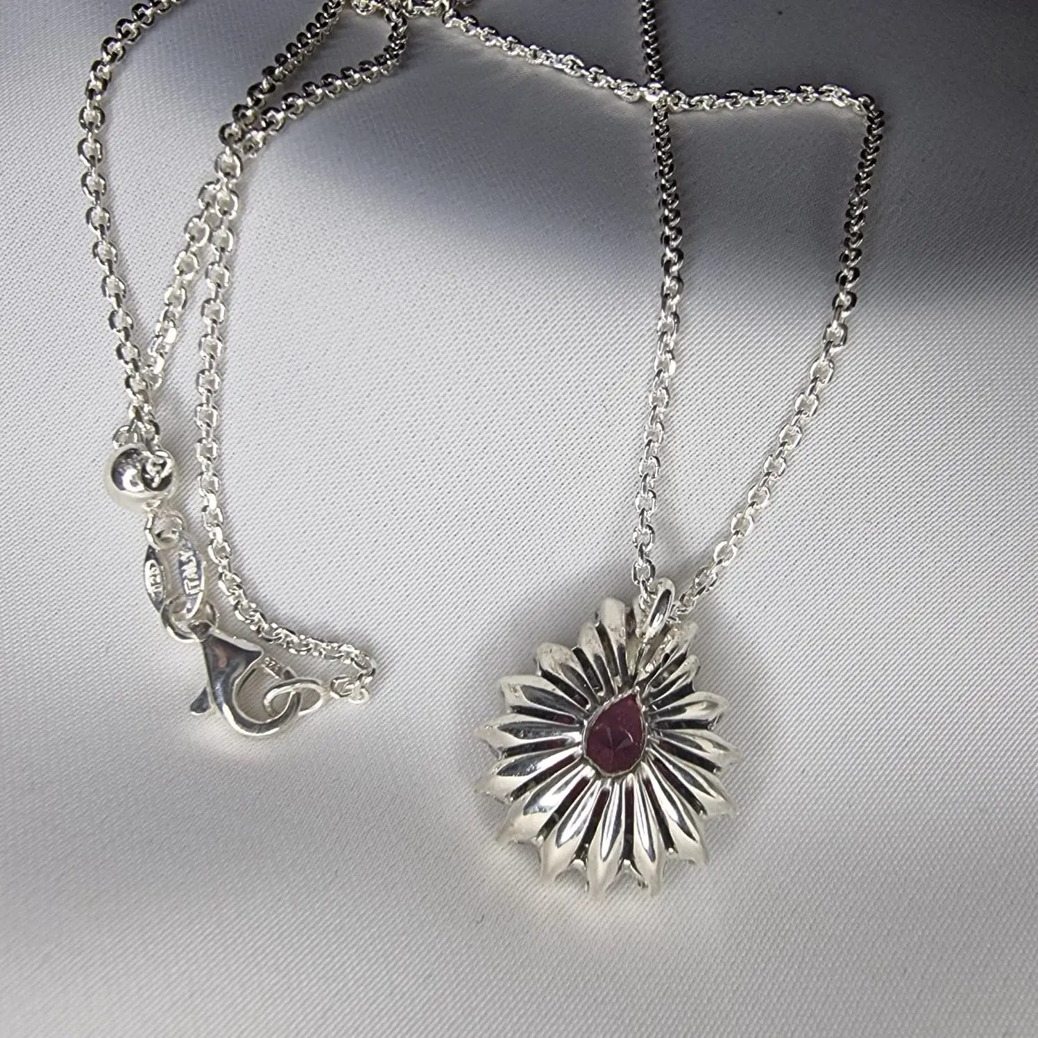 a close up of a necklace with a flower on it