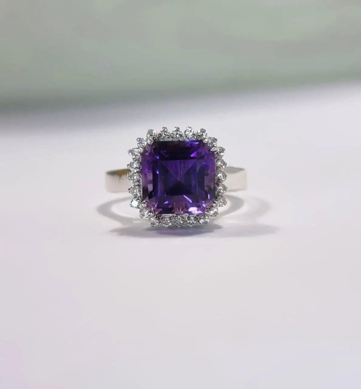 a ring with a purple stone surrounded by diamonds