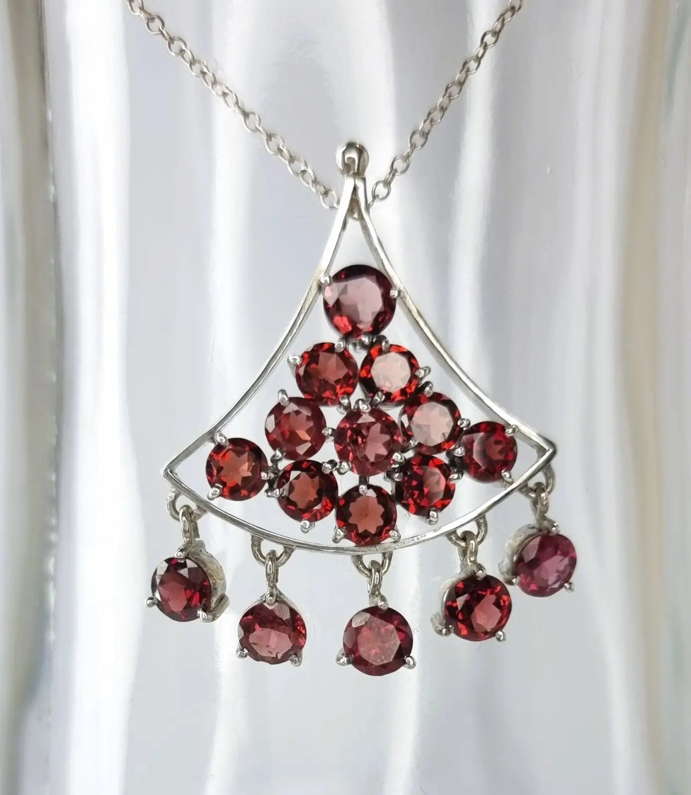 a silver necklace with red stones hanging from it