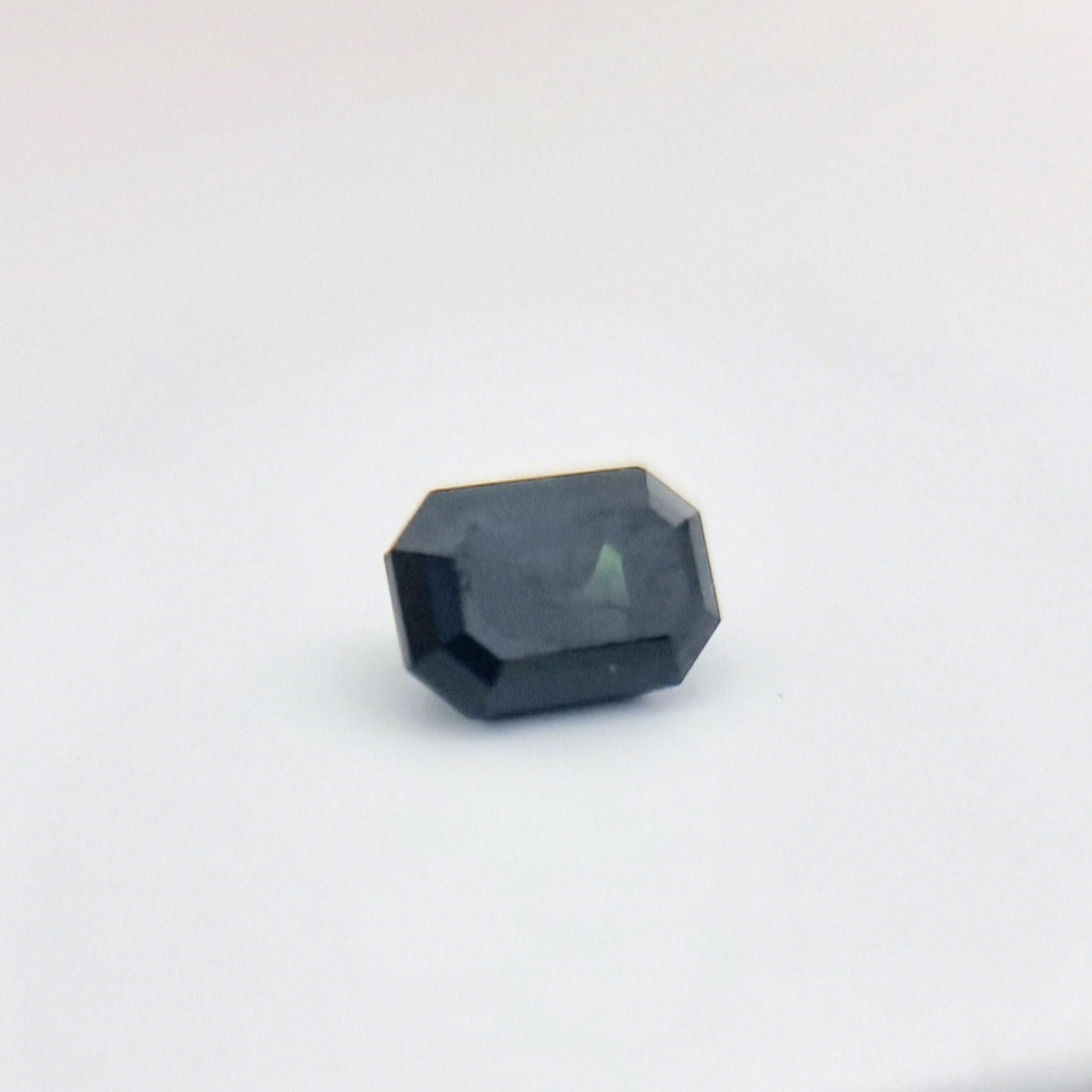 Natural greenish blue sapphire 1.84 ctw with rectangular cut, showcasing a unique blend of green and blue tones for artistic jewelry designs.