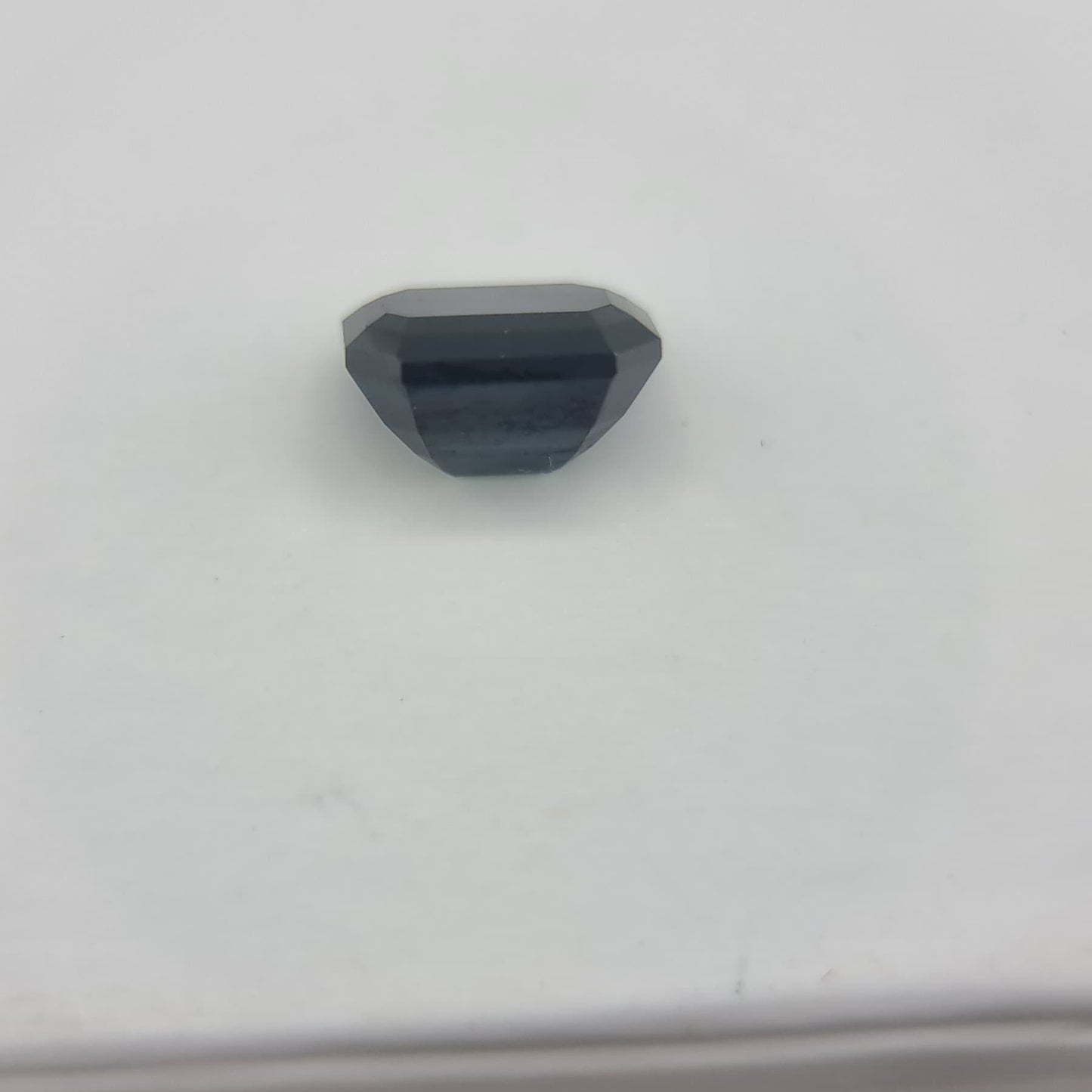Back view of rectangular cut 1.84 ctw greenish blue sapphire, highlighting its polished facets and collectible gemstone quality.