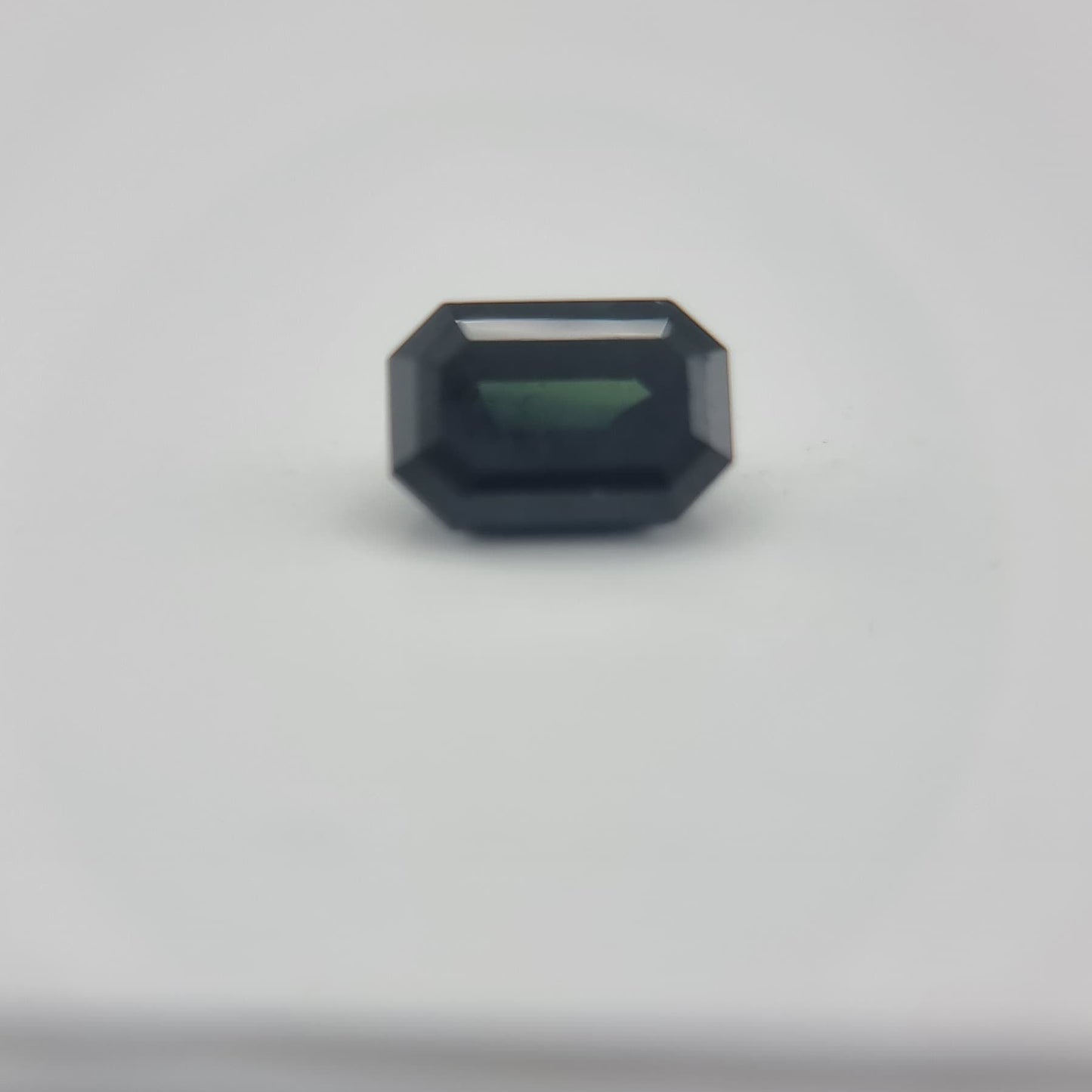 Close-up of 1.84 ctw rectangular greenish blue sapphire with natural hues, perfect for gemstone collectors and creative arts use.