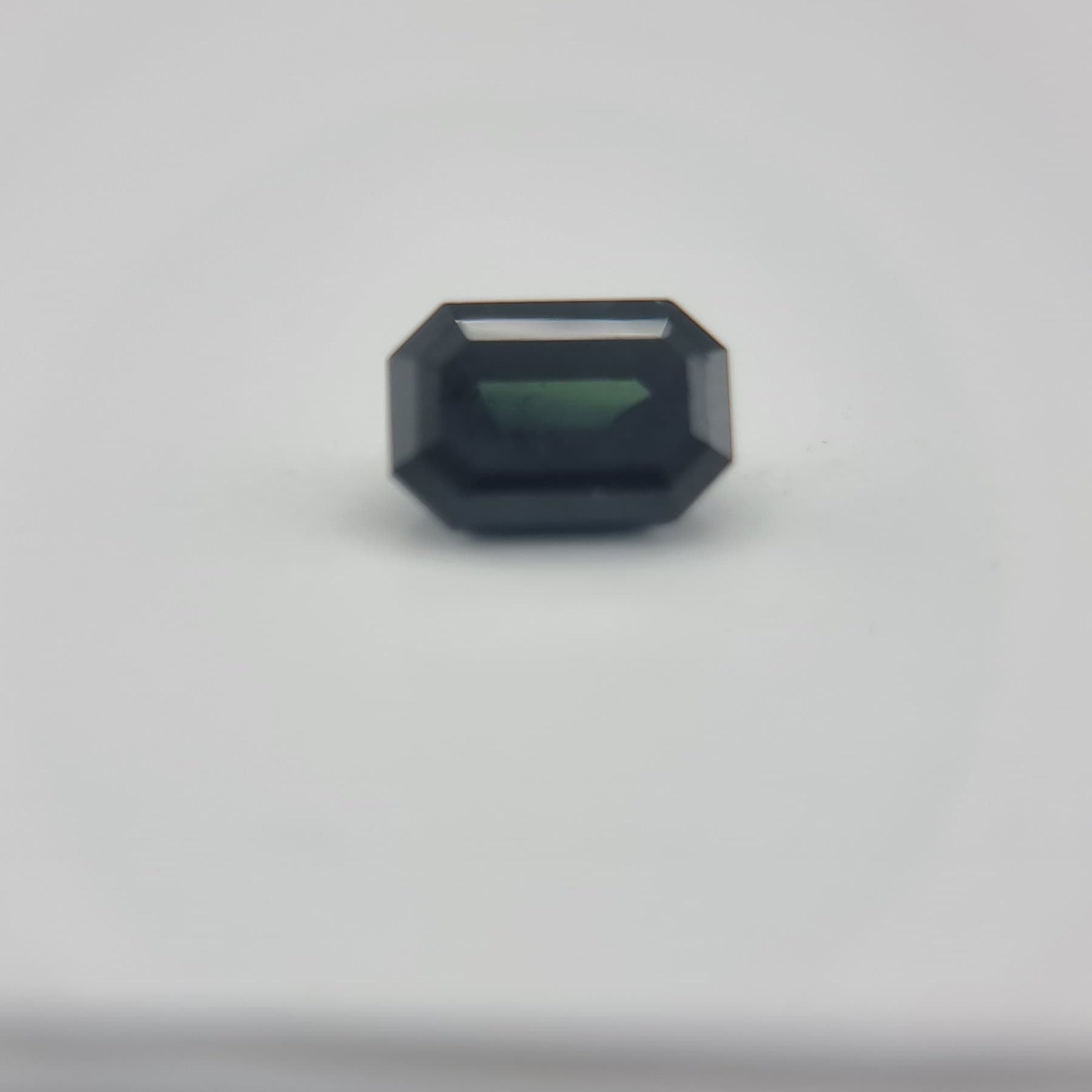 Close-up of 1.84 ctw rectangular greenish blue sapphire with natural hues, perfect for gemstone collectors and creative arts use.