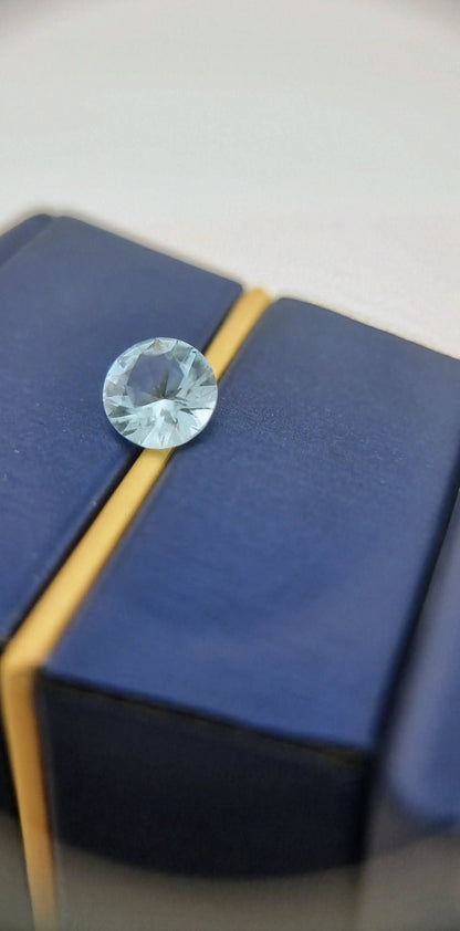 Buy Aquamarine Loose Gemstone - Premium Quality Gems resting on a blue and gold jewelry box, showcasing its clarity and brilliance.