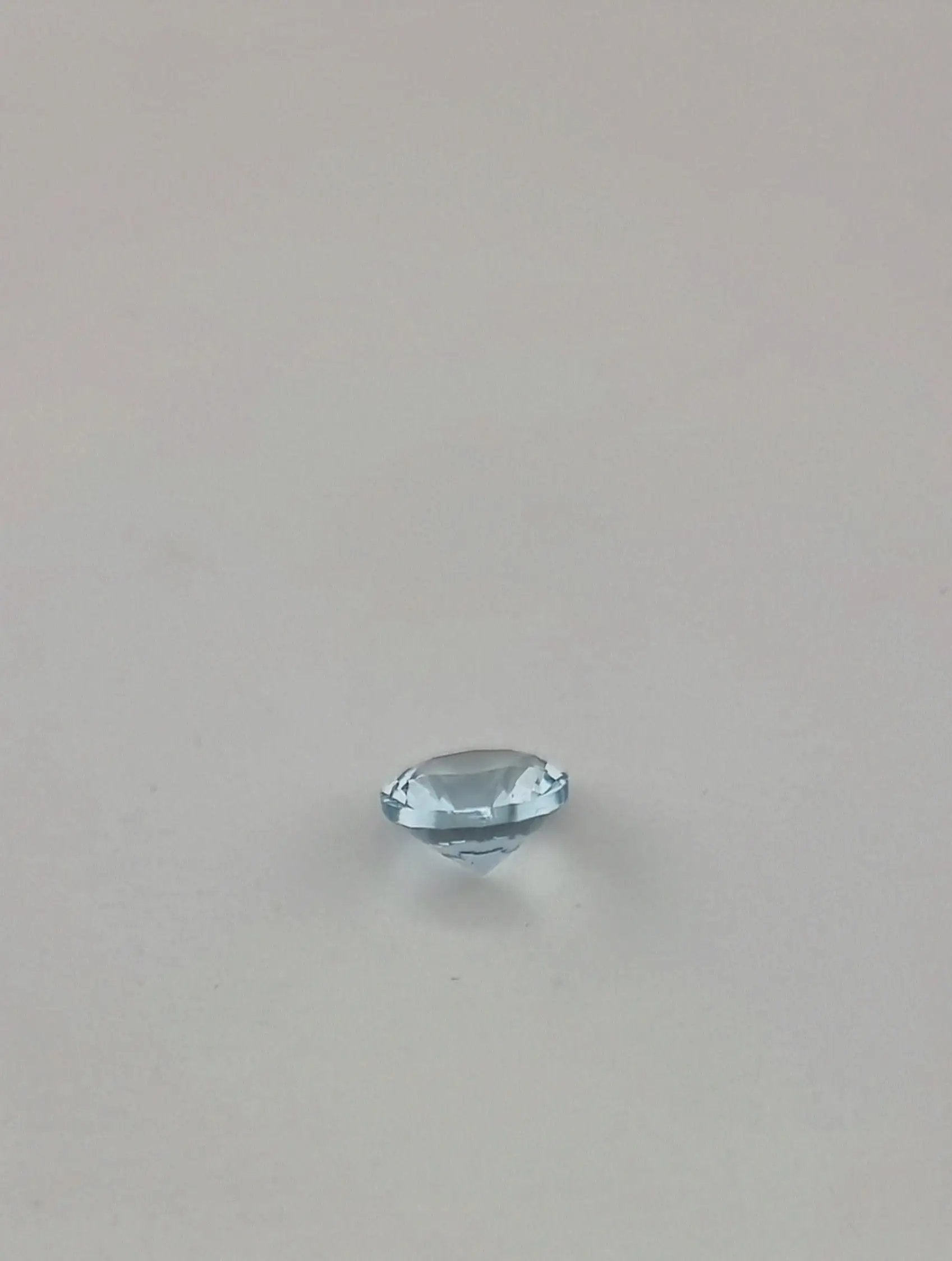 Side view of a premium aquamarine loose gemstone with a faceted cut, highlighting its depth and transparency.