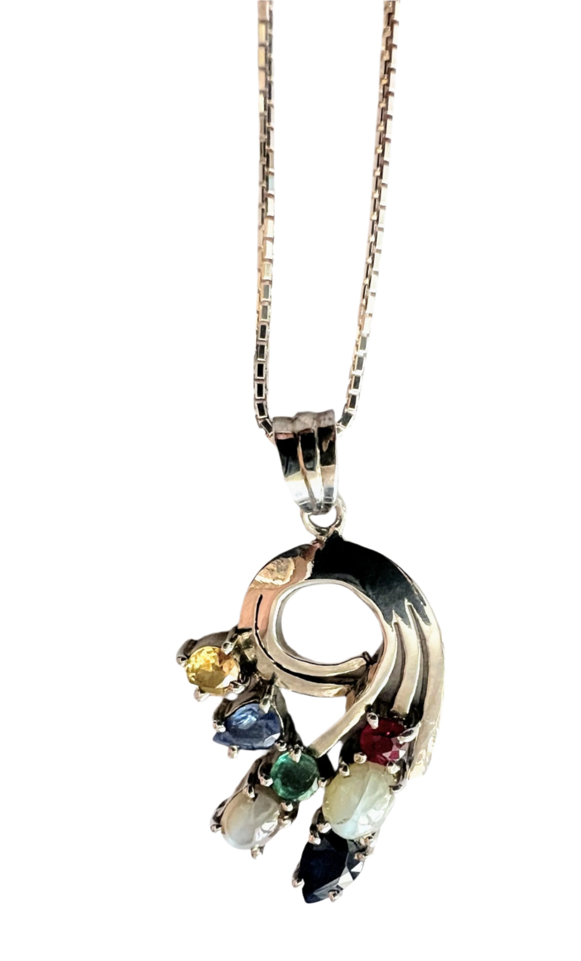 Luxury Multigem Swirling Infinity Pendant Necklace with floral motif, showcasing ruby, emerald, blue and pink sapphires, and cat's-eyes on a silver chain.