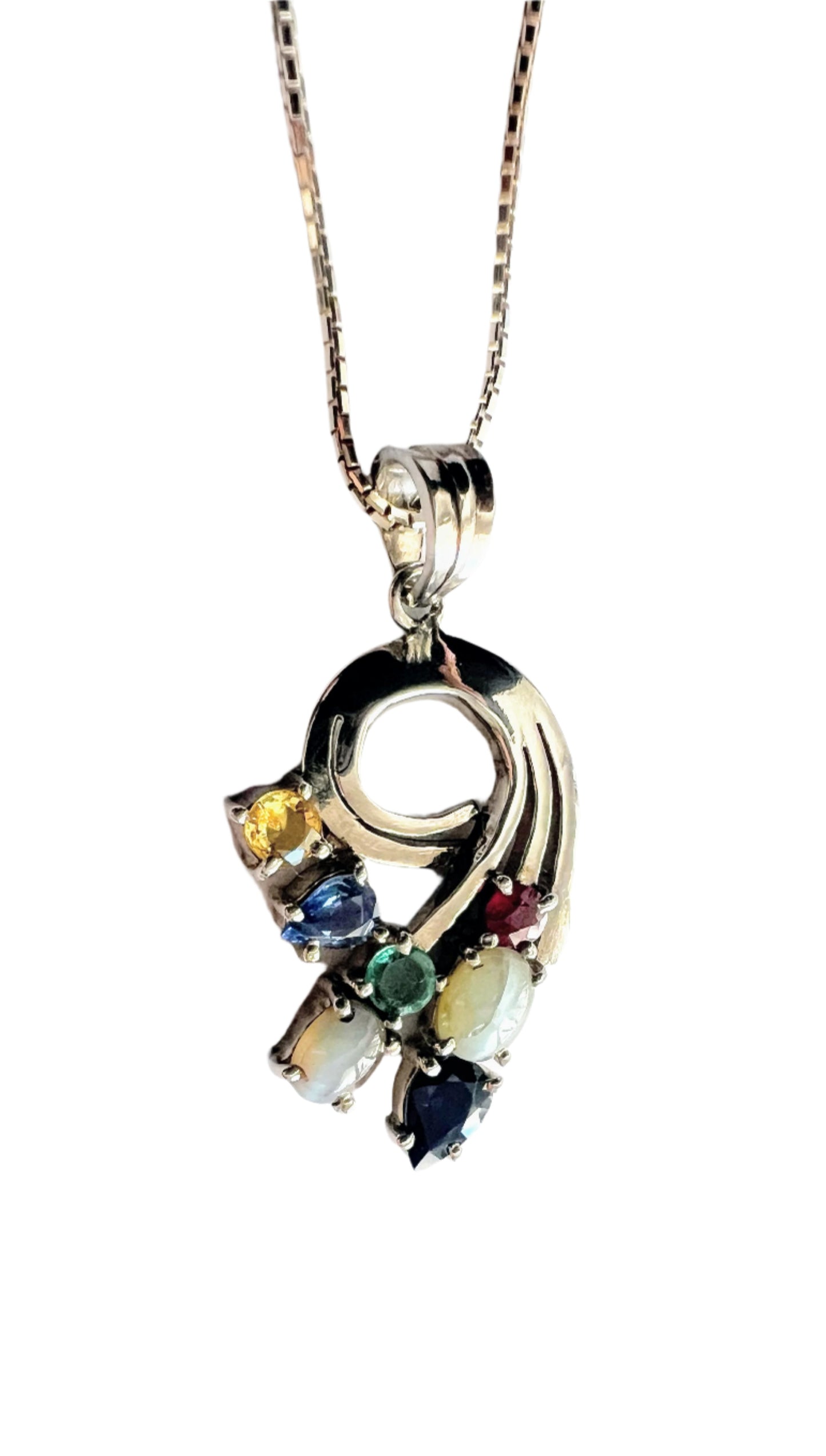 Close-up of Multigem Swirling Infinity Pendant Necklace with ruby, sapphires, emerald, and cat's-eyes in a floral swirl design. Fine jewelry for elegant styling.