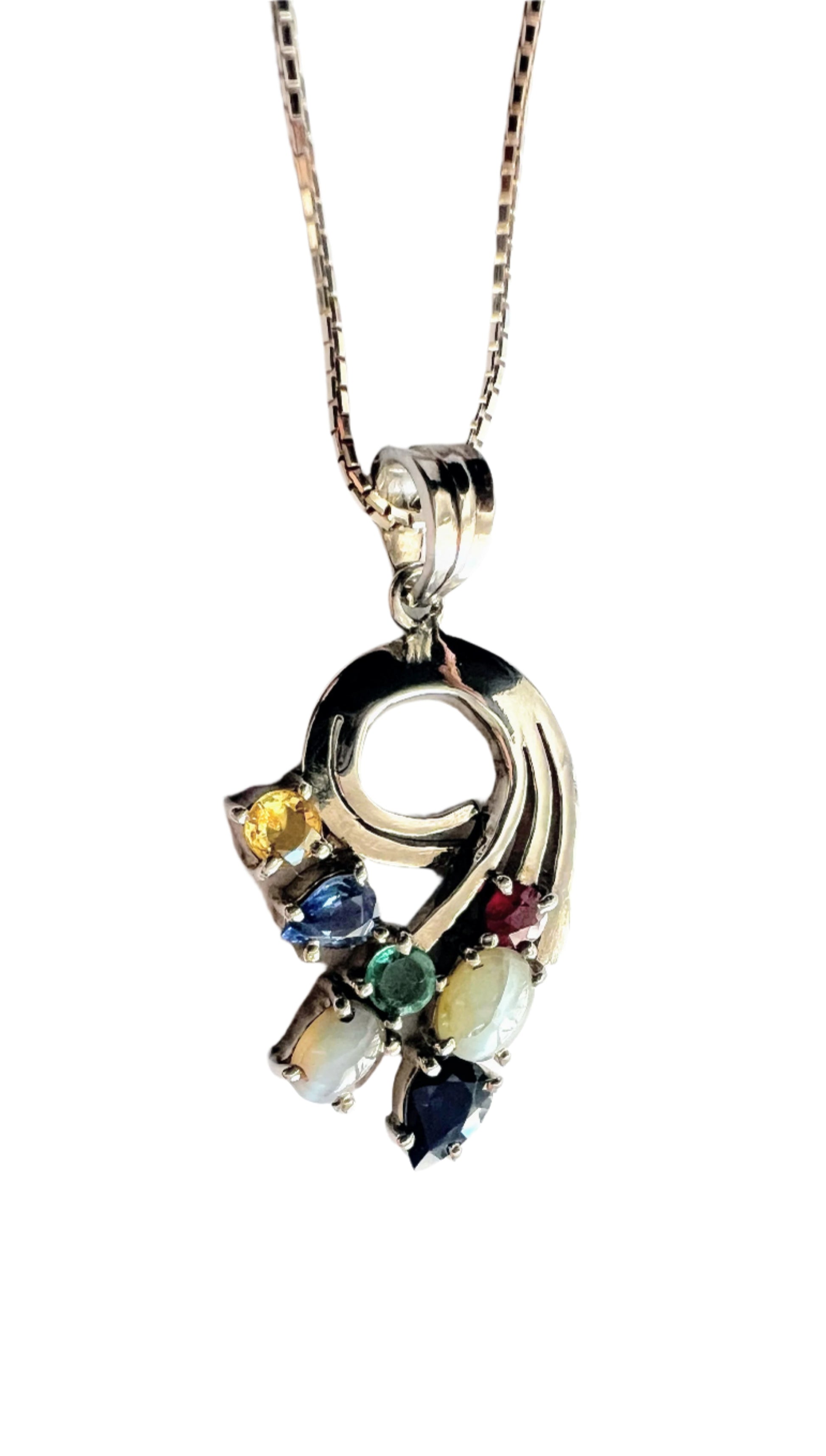 Close-up of Multigem Swirling Infinity Pendant Necklace with ruby, sapphires, emerald, and cat's-eyes in a floral swirl design. Fine jewelry for elegant styling.