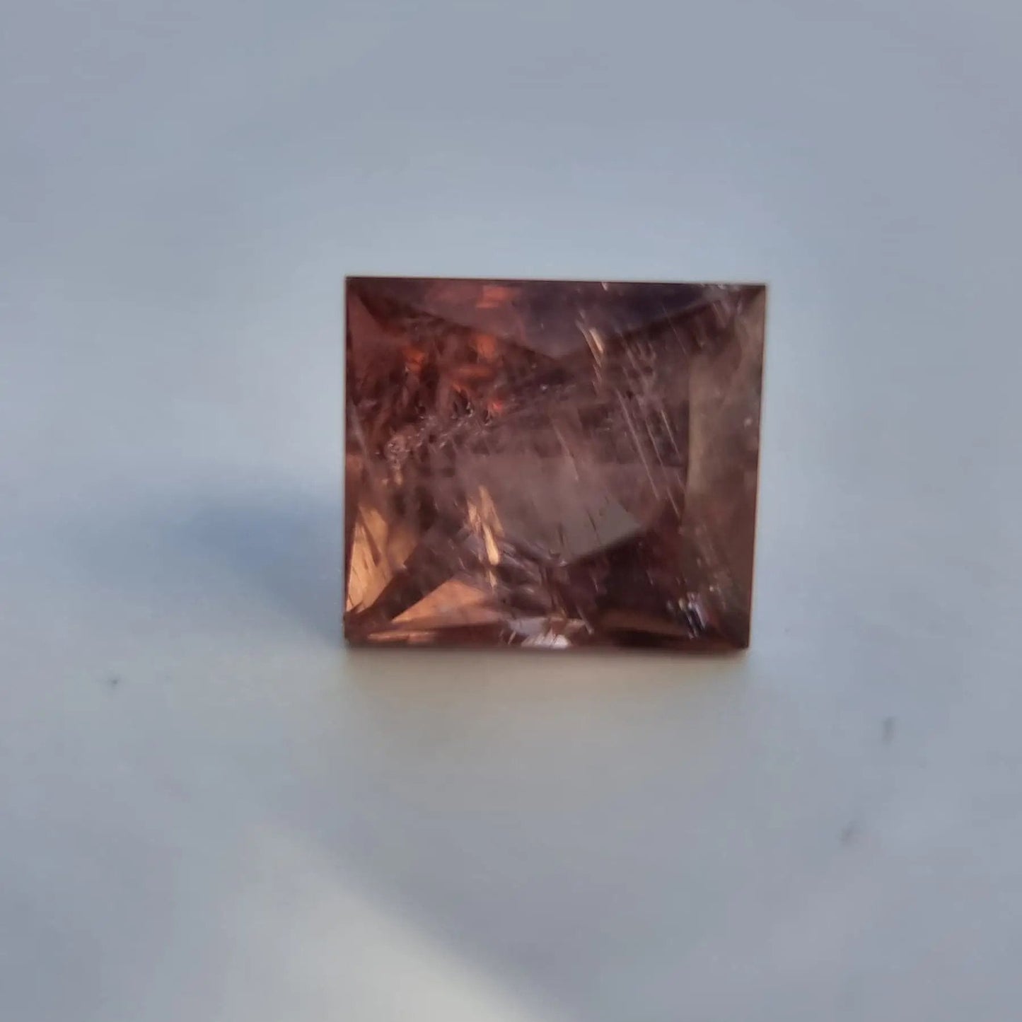 Square cut red tourmaline gemstone with visible inclusions and warm reddish-pink color, suitable for fine jewelry design.