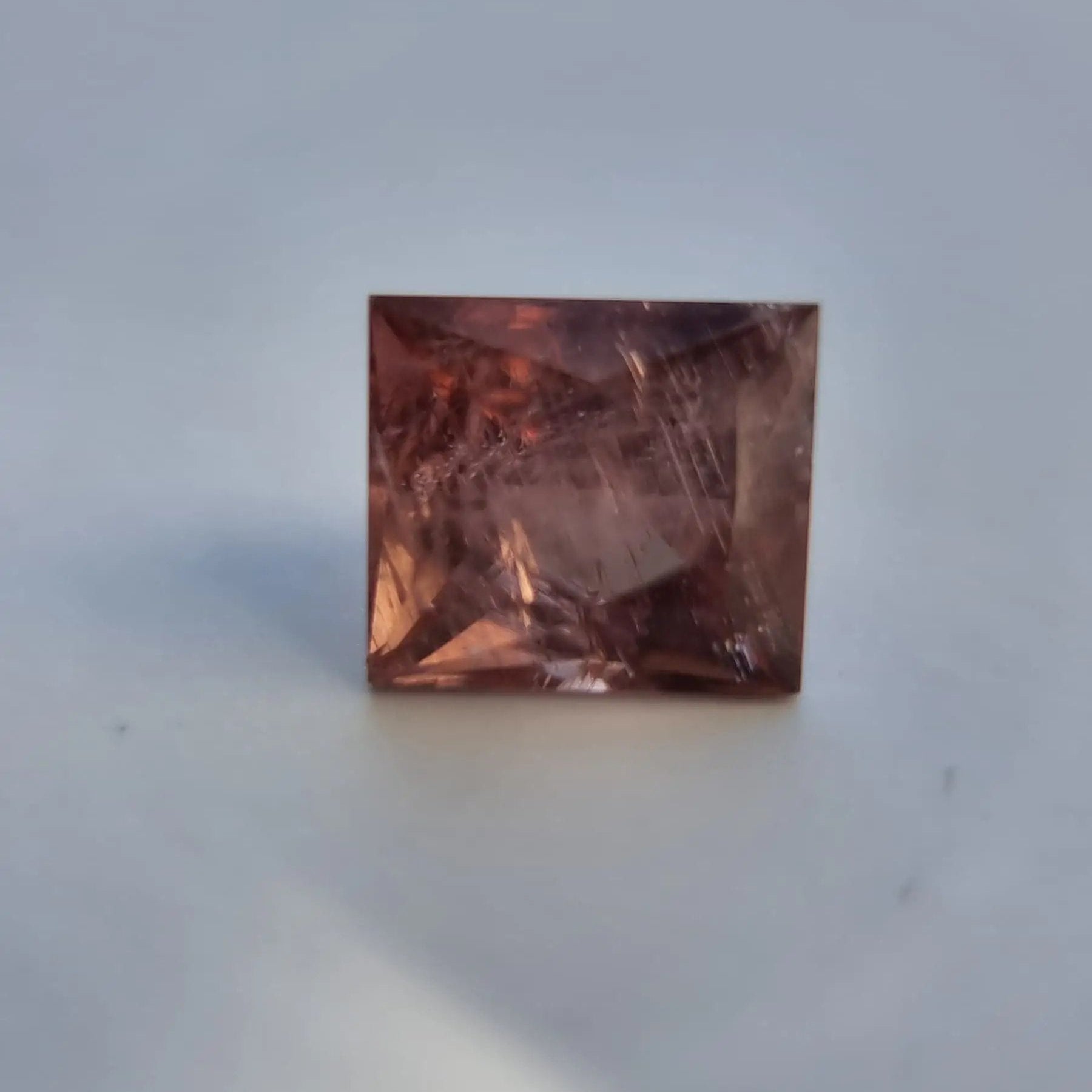 Square cut red tourmaline gemstone with visible inclusions and warm reddish-pink color, suitable for fine jewelry design.