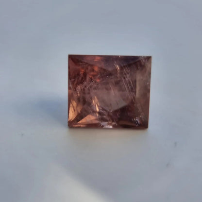Square cut red tourmaline gemstone with visible inclusions and warm reddish-pink color, suitable for fine jewelry design.