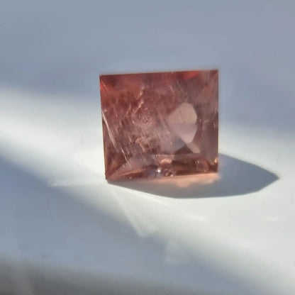 5.13 carat red square cut tourmaline gemstone reflecting light with warm reddish tones, collectible quality.