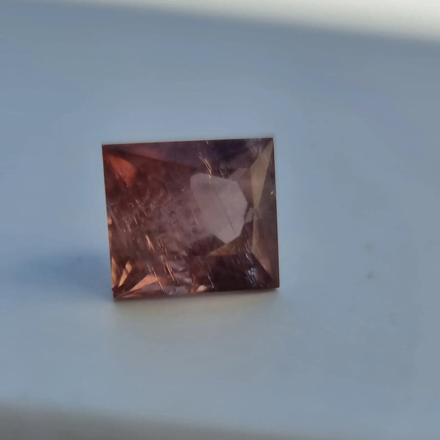 Square cut red tourmaline gemstone with deep red-pink hue and visible internal structure, 5.13 carats.