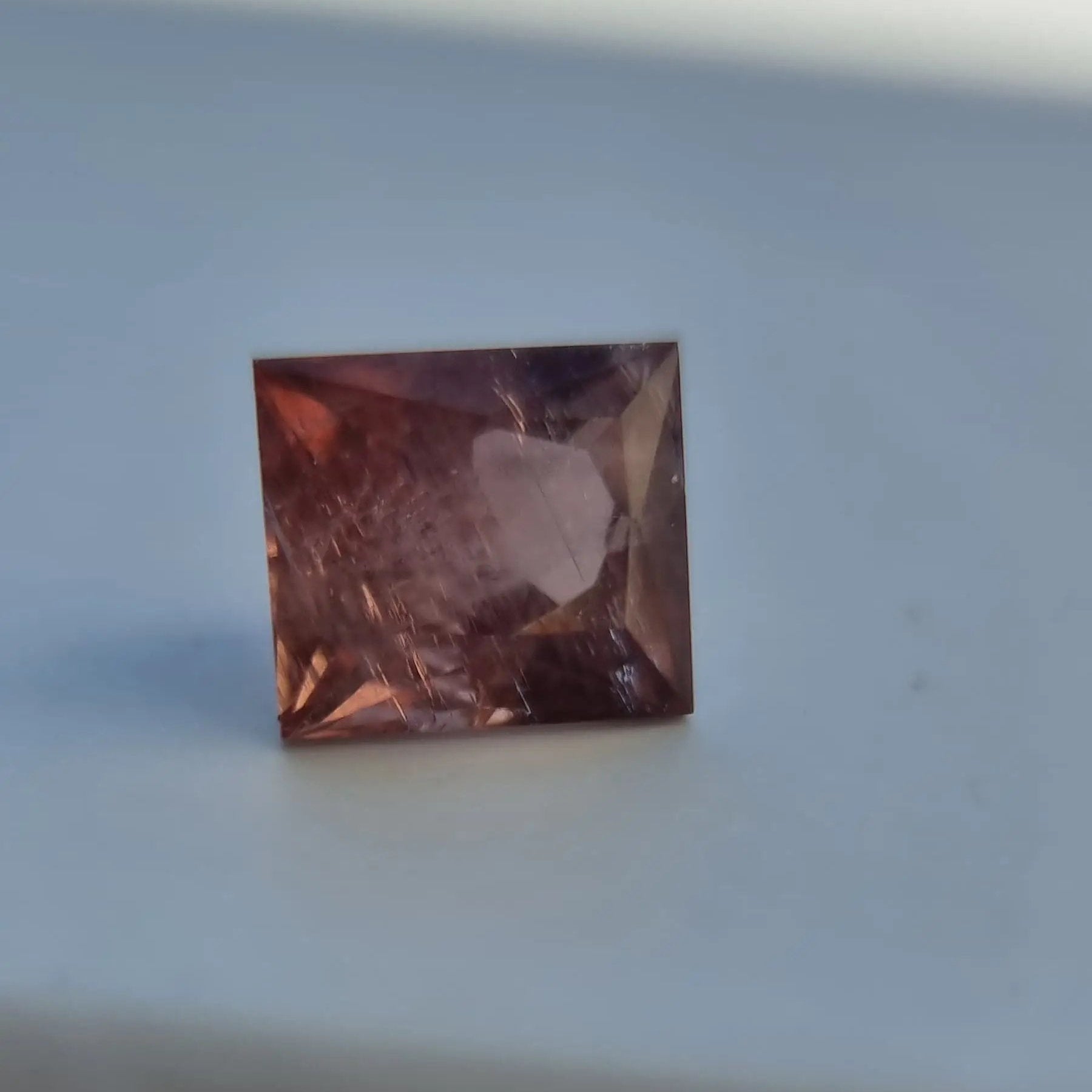 Square cut red tourmaline gemstone with deep red-pink hue and visible internal structure, 5.13 carats.