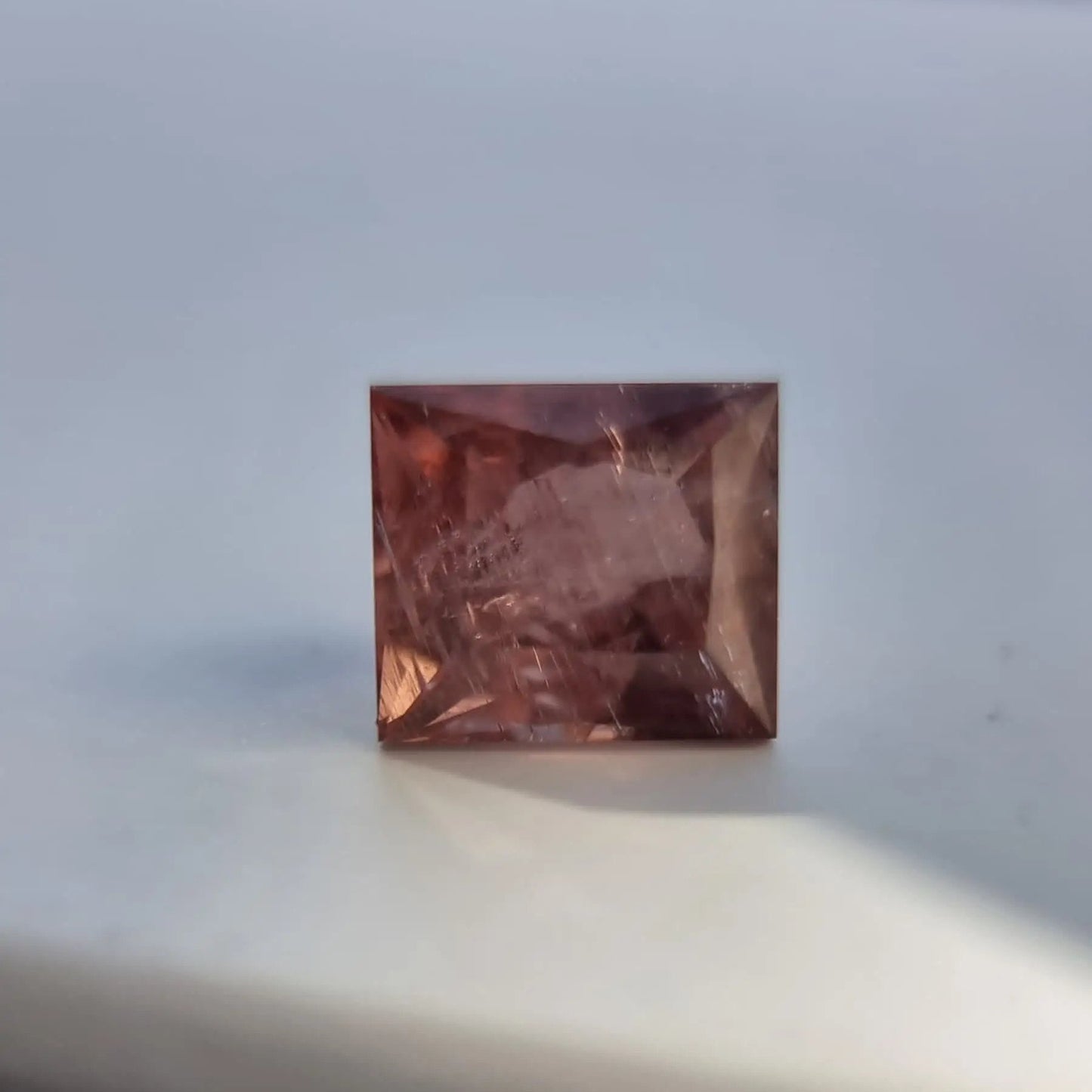 Loose red tourmaline gemstone in square cut, 5.13 carats, with autumn-inspired tones and natural inclusions.