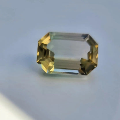 Emerald cut 6.1ct bi-color tourmaline gemstone with yellow-green gradient, perfect for gemstone collectors and artisans.