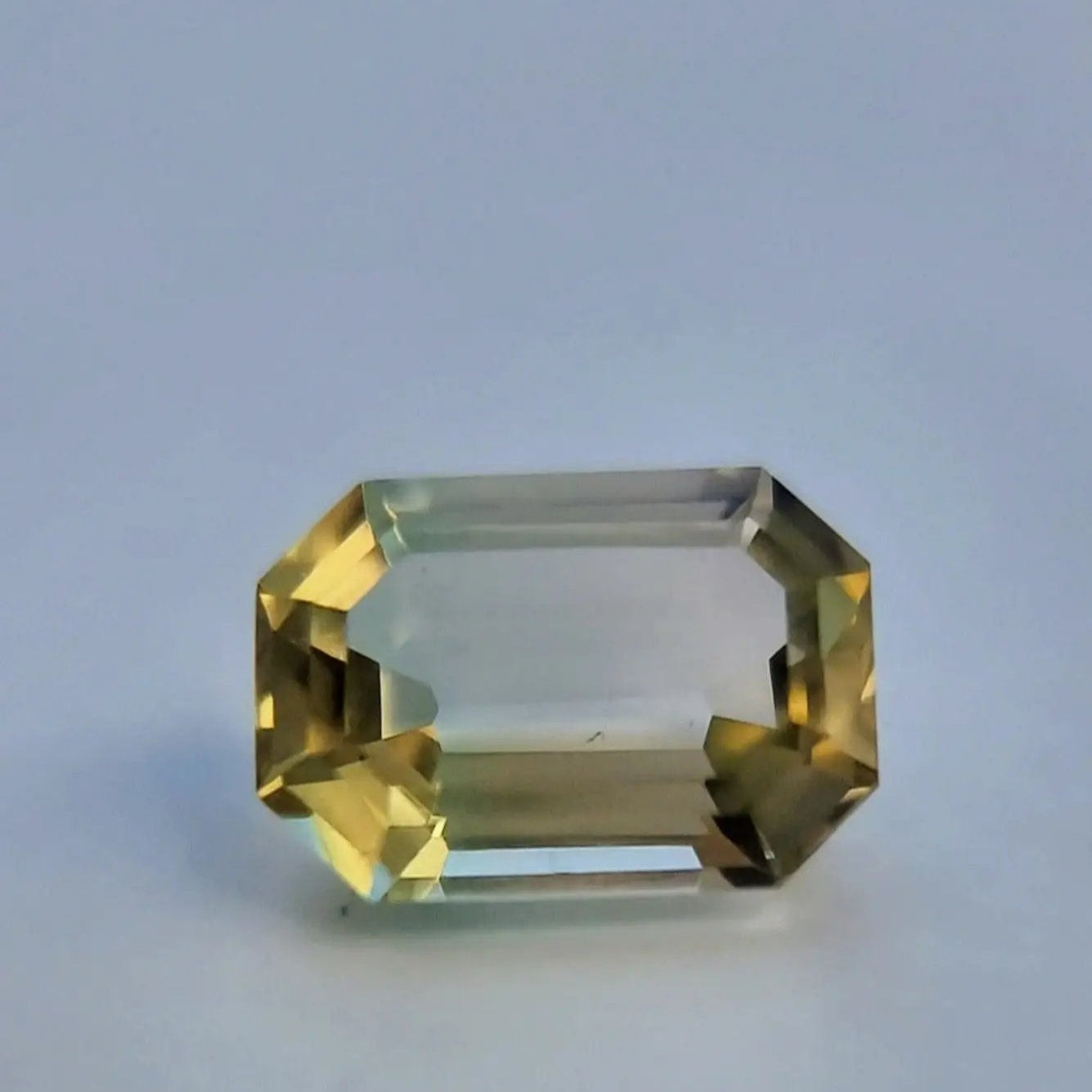 Natural 6.1ct tourmaline gemstone in emerald cut, featuring a striking bi-color transition from yellow to green.
