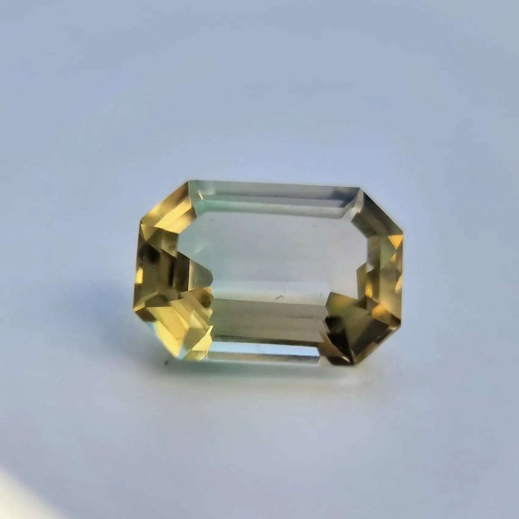 Bi-color tourmaline gemstone, 6.1ct emerald cut, with vivid yellow and green tones, suitable for unique jewelry designs.