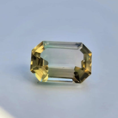 Bi-color tourmaline gemstone, 6.1ct emerald cut, with vivid yellow and green tones, suitable for unique jewelry designs.