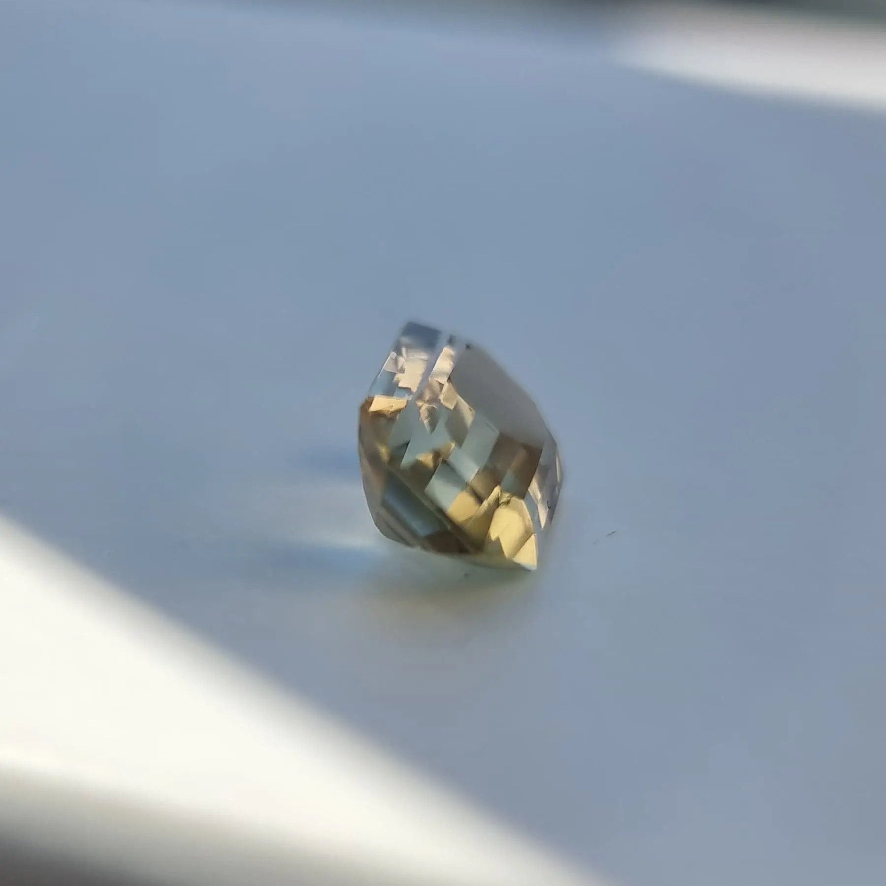 Side view of 6.1ct emerald cut bi-color tourmaline gemstone, highlighting its faceted structure and color zoning.