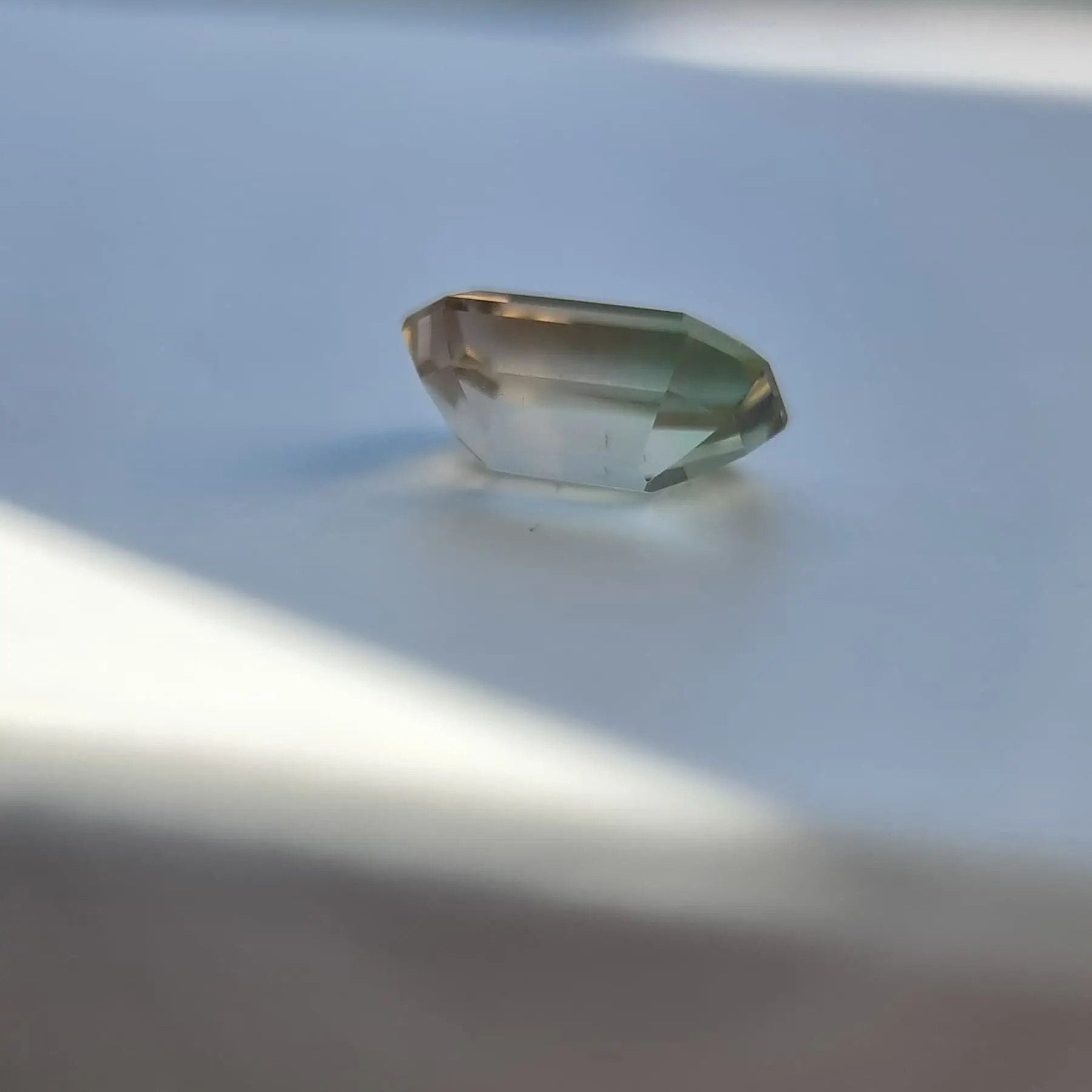 Profile angle of 6.1ct natural bi-color tourmaline gemstone in emerald cut, showing depth and color transition.
