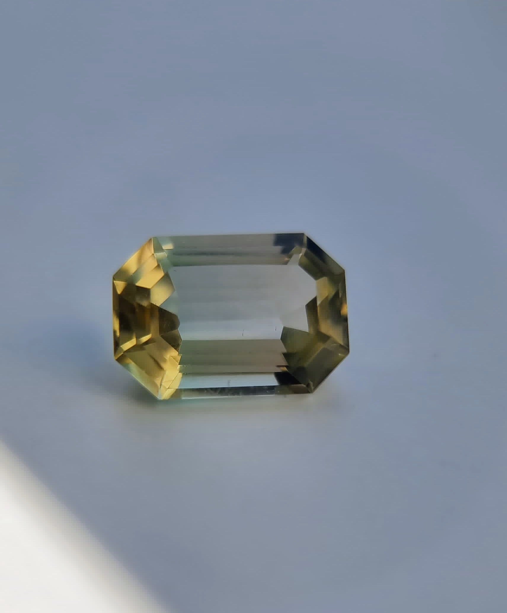 Close-up of 6.1ct emerald cut bi-color tourmaline, featuring untreated clarity and a rare yellow to green color blend.