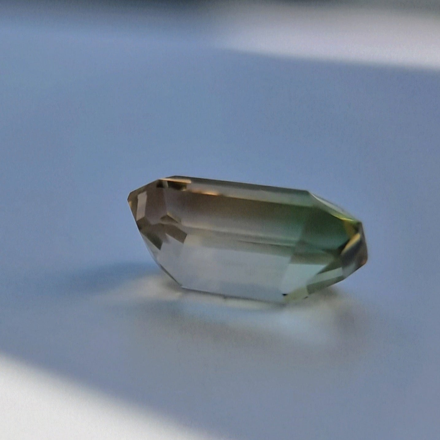 Angled side view of 6.1ct emerald cut tourmaline gemstone with natural yellow-green bi-color gradient.