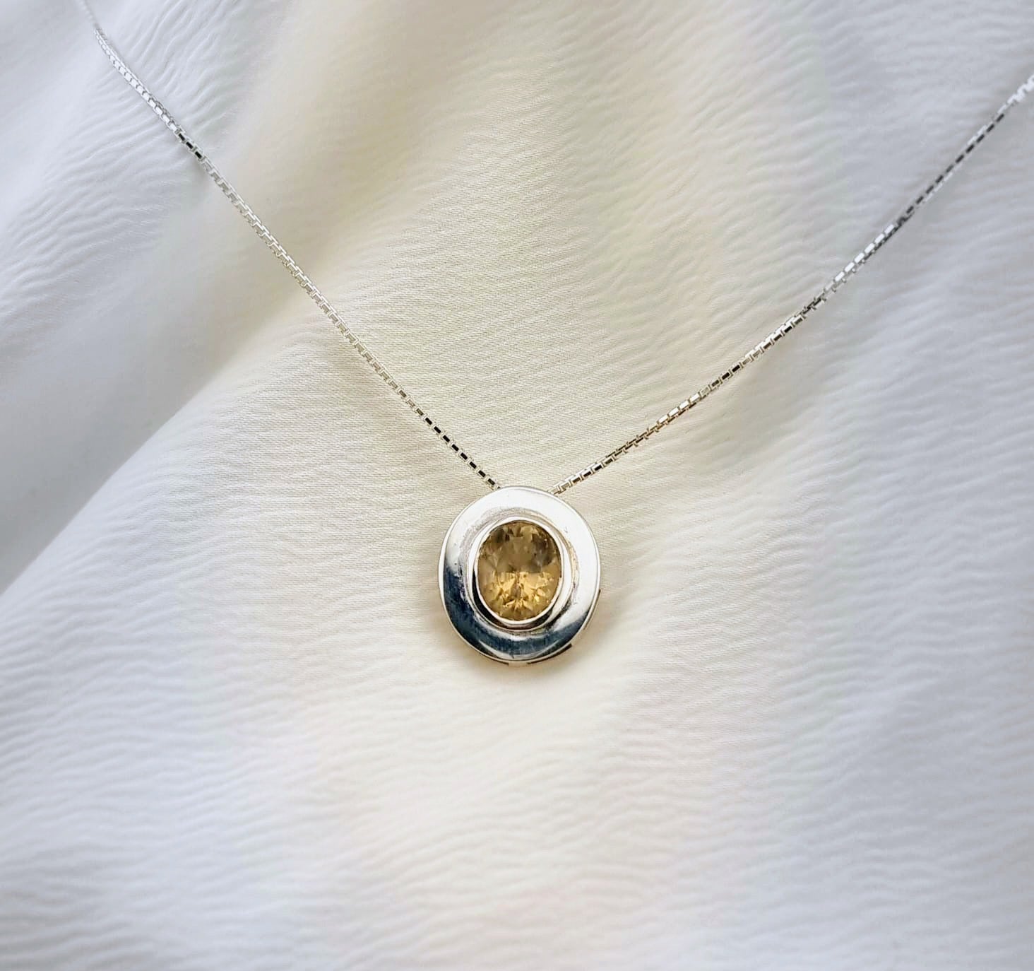 Sterling silver necklace with a natural citrine pendant, styled on a soft white surface to highlight its refined and timeless appeal.