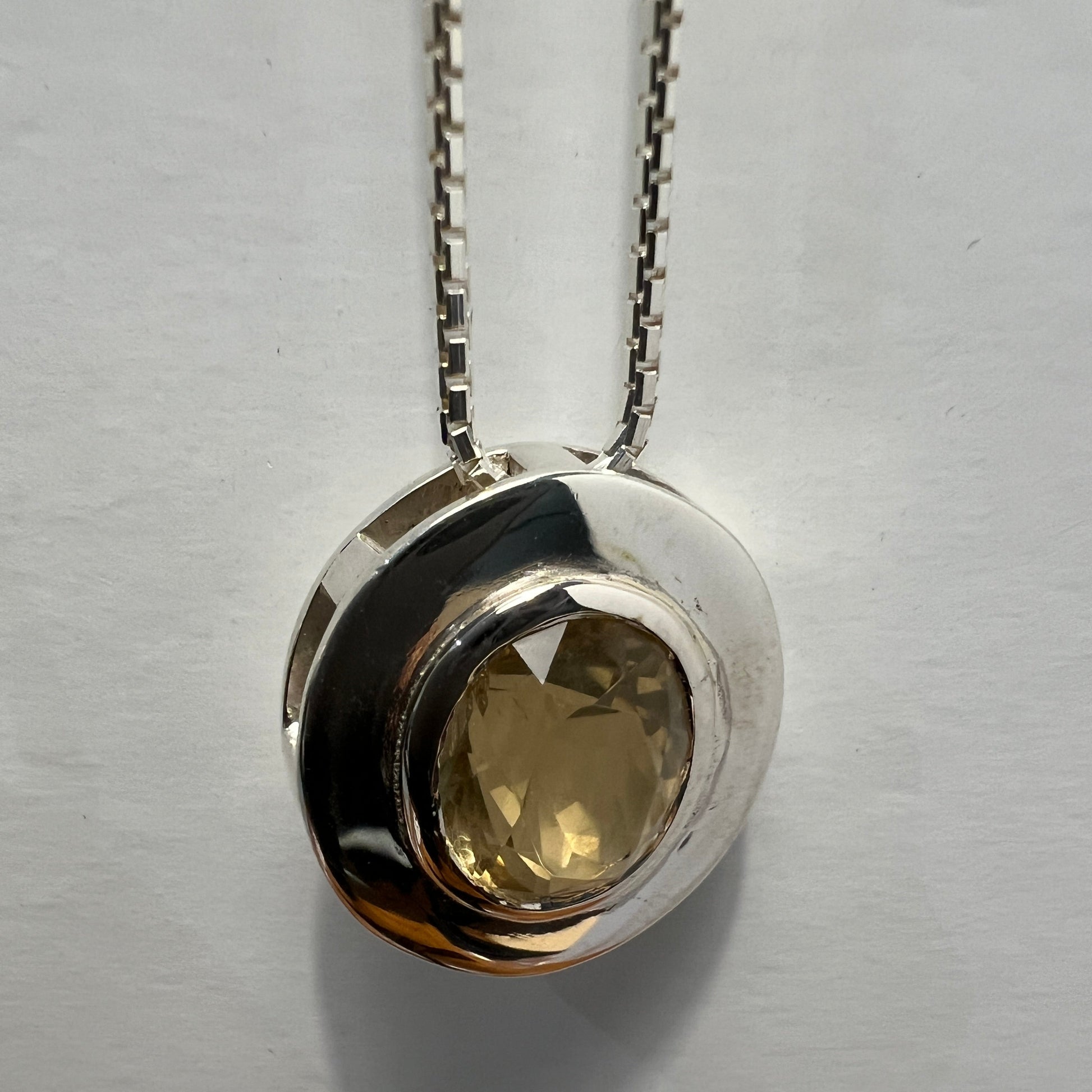 Close-up of citrine pendant necklace in sterling silver with a faceted gemstone, emphasizing the handcrafted bezel and polished finish.