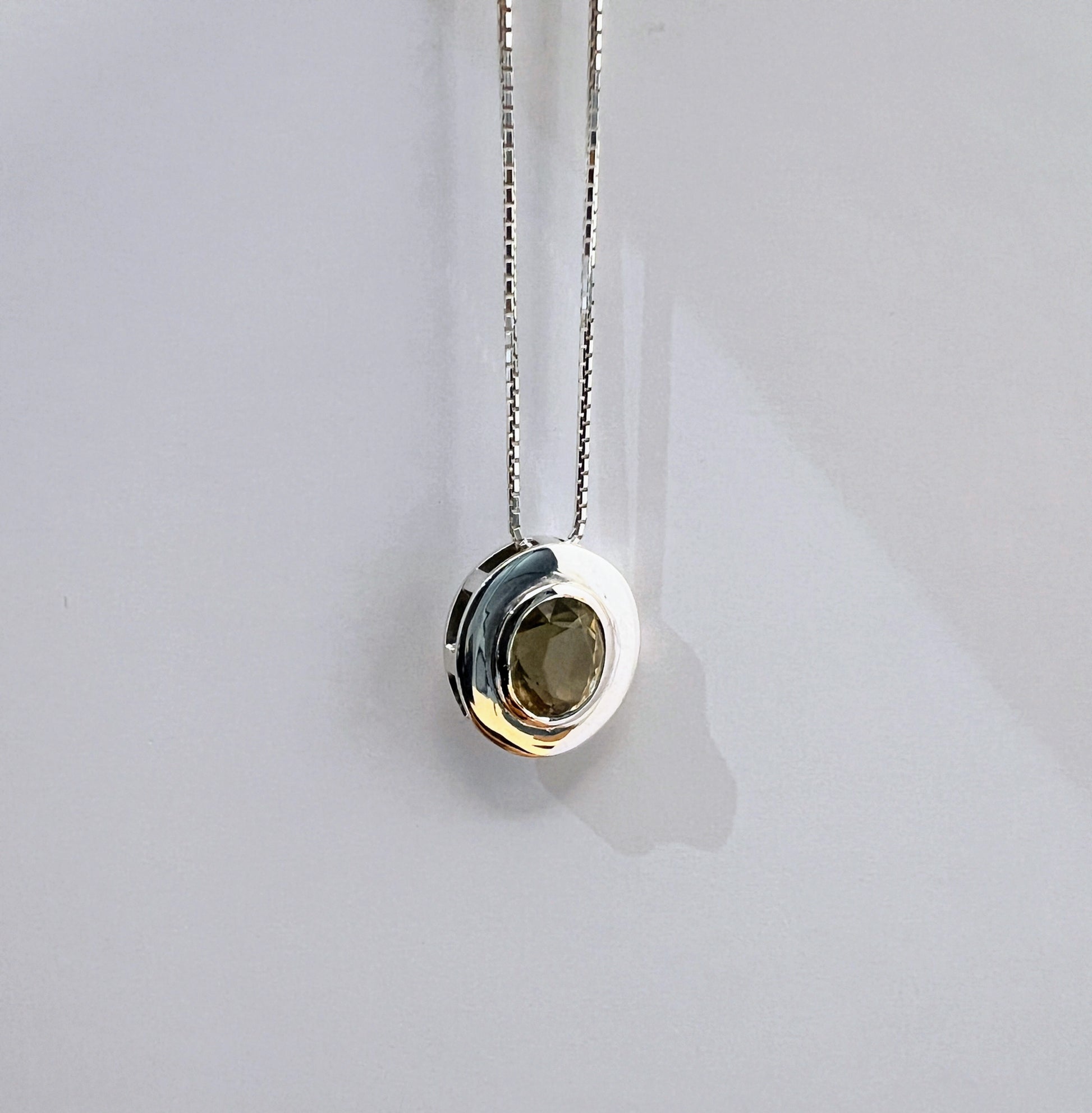 Minimalist citrine pendant necklace in sterling silver with a centered natural gemstone, suspended on a sleek box chain against a plain background.