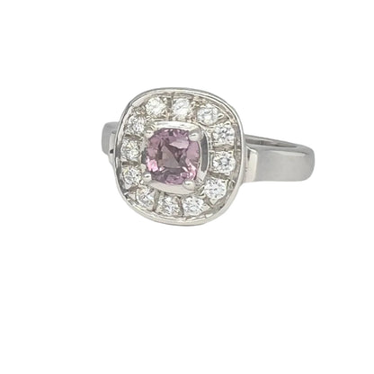 Pink sapphire engagement ring in platinum silver with cushion-cut center and diamond halo. A luxurious and unique jewelry piece for any occasion.