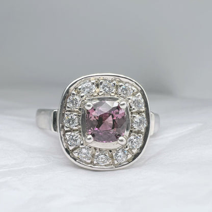 1ct cushion pink sapphire ring surrounded by sparkling white stones in a platinum silver band. A standout accessory in fine jewelry collections.