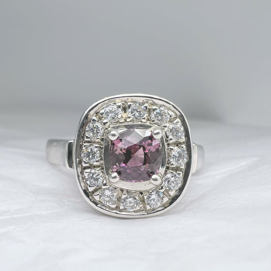 1ct cushion pink sapphire ring surrounded by sparkling white stones in a platinum silver band. A standout accessory in fine jewelry collections.