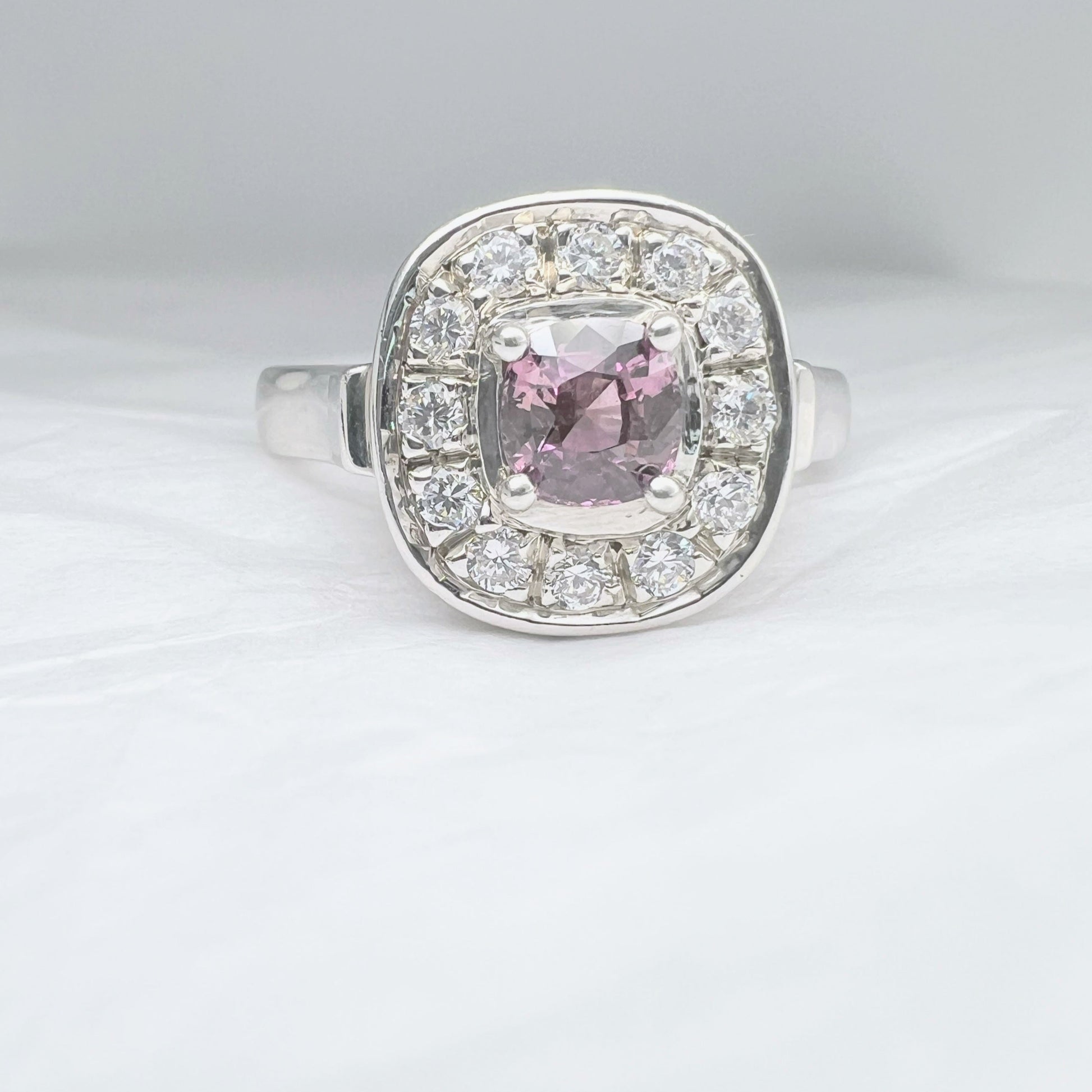 Pink sapphire platinum silver engagement ring with cushion-cut center and diamond halo. A refined and elegant jewelry piece for special moments.