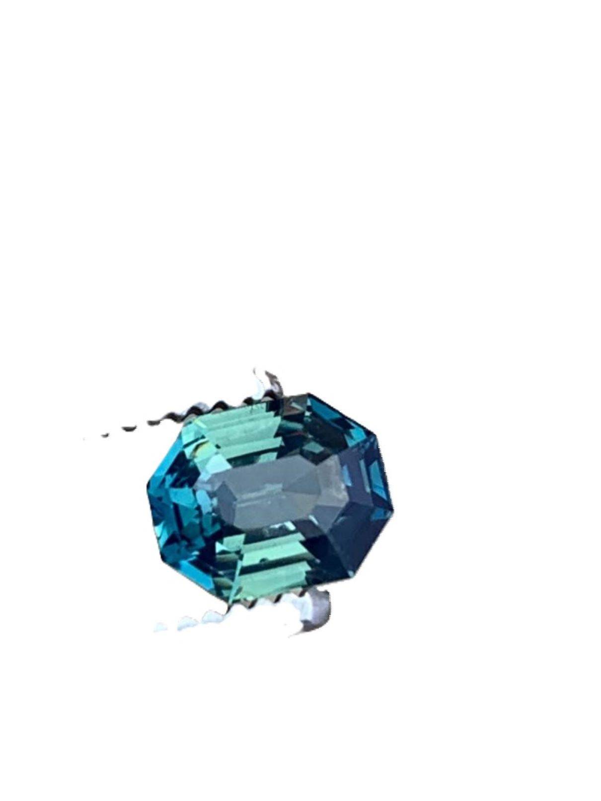 Loose 2.5ct radiant cut blue teal sapphire gemstone displayed against a white background, highlighting its exquisite cut and color.