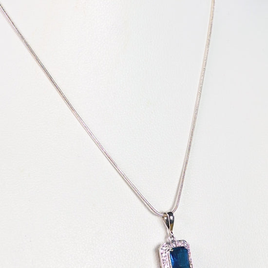 a necklace with a blue stone on a white background