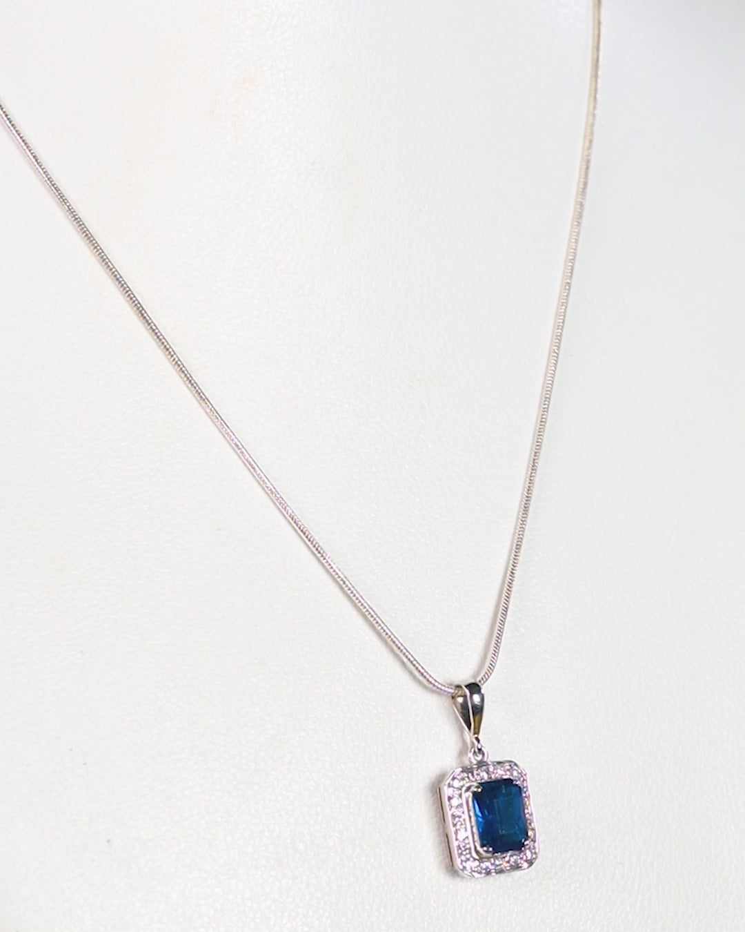 a necklace with a blue stone on a white background