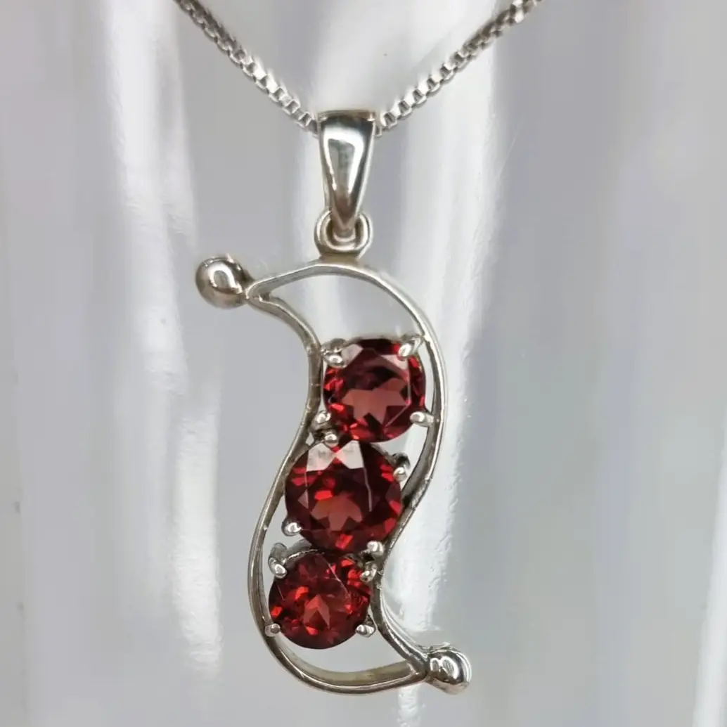 a pendant with two red stones hanging from a chain