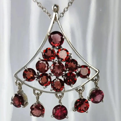 a silver necklace with red stones hanging from it