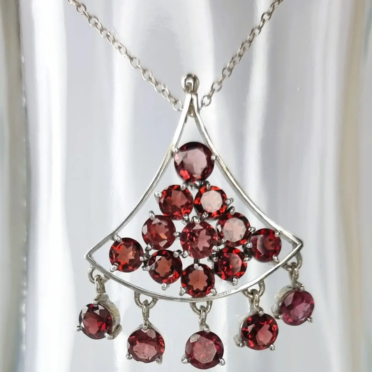 a silver necklace with red stones hanging from it