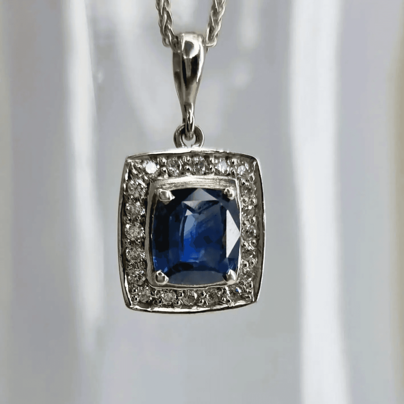 a pendant with a blue stone surrounded by diamonds