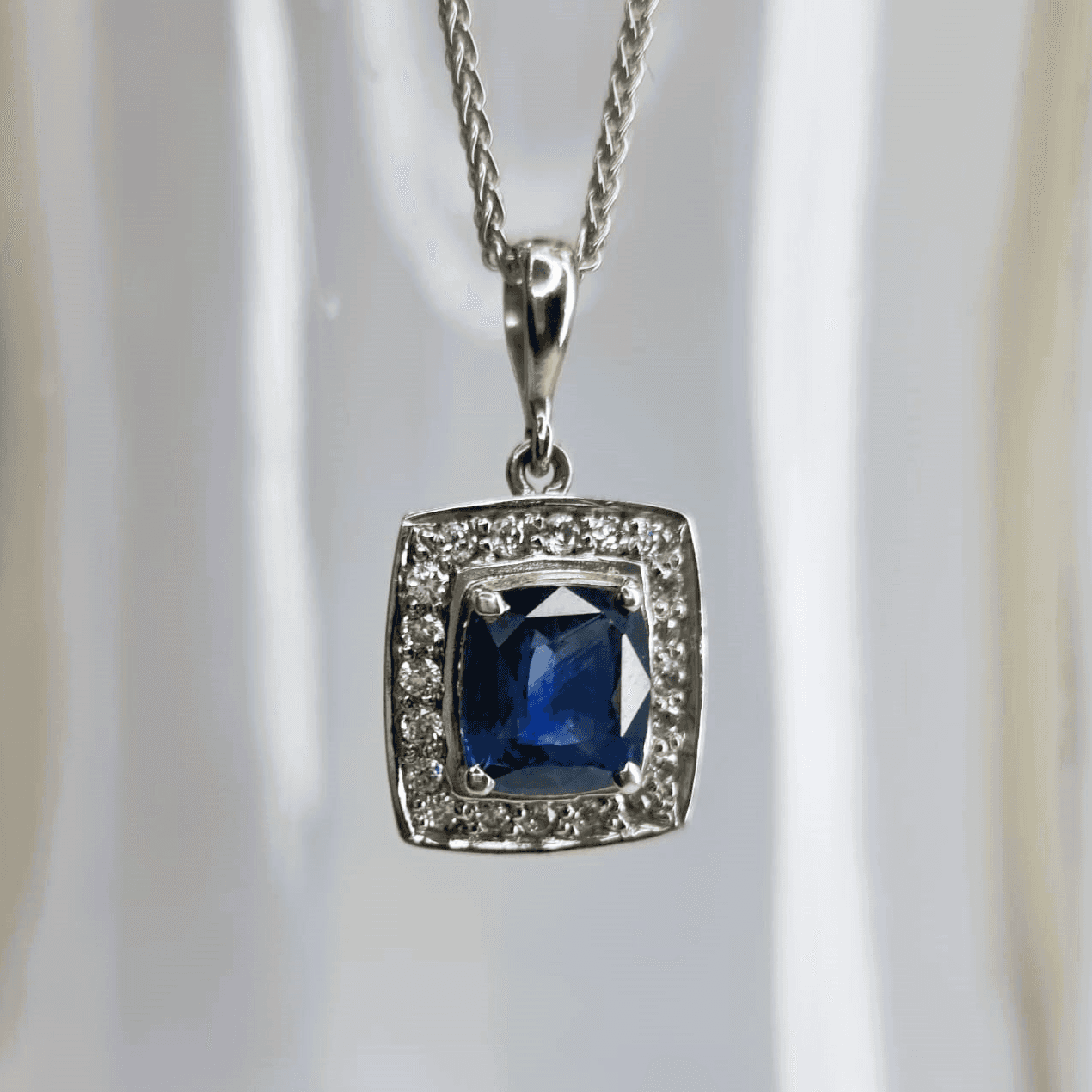 a necklace with a square shaped blue stone surrounded by diamonds